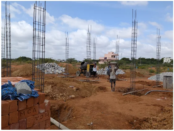KSR House Contractors site showing reinforced column cages, construction materials and active structural work